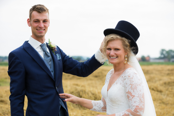 Bruid en bruidegom in het veld met hoed